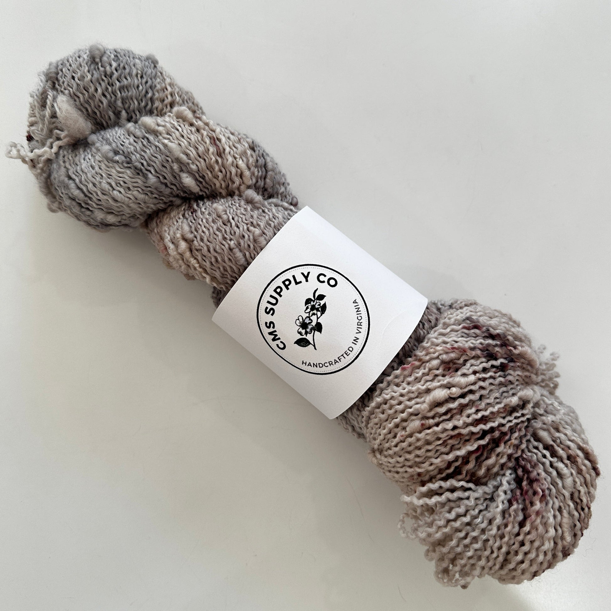 Ball of gray yarn with a label on a white background