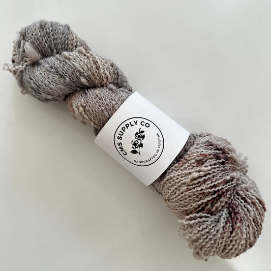 Ball of gray yarn with a label on a white background