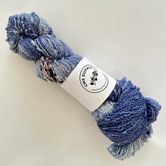 Blue skein of yarn with a label on a white background